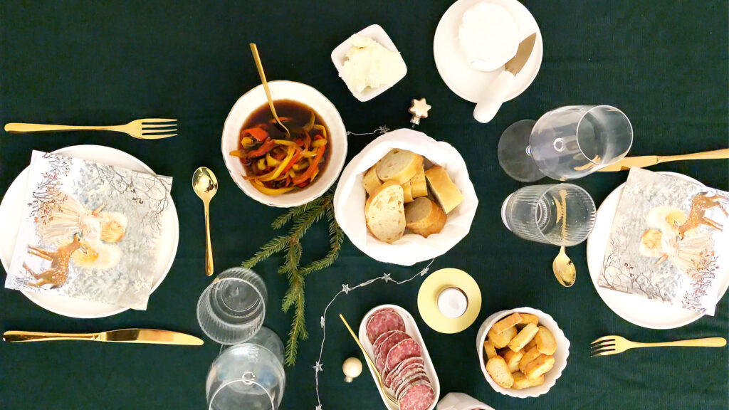 Gedeckter Tisch mit Antipasti mit Paprika, Frischkäse, Salami, Baguette